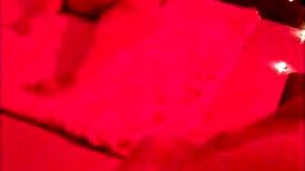 Brunette chubby girl sits on big dick under red light, contrasting her small tits with the intense action.