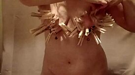 slave performs auto-session with clamps, belt, and dildo outdoors