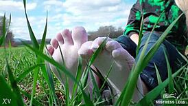 Goddess displays cute curly toes in white socks beneath jeans on spring grass field